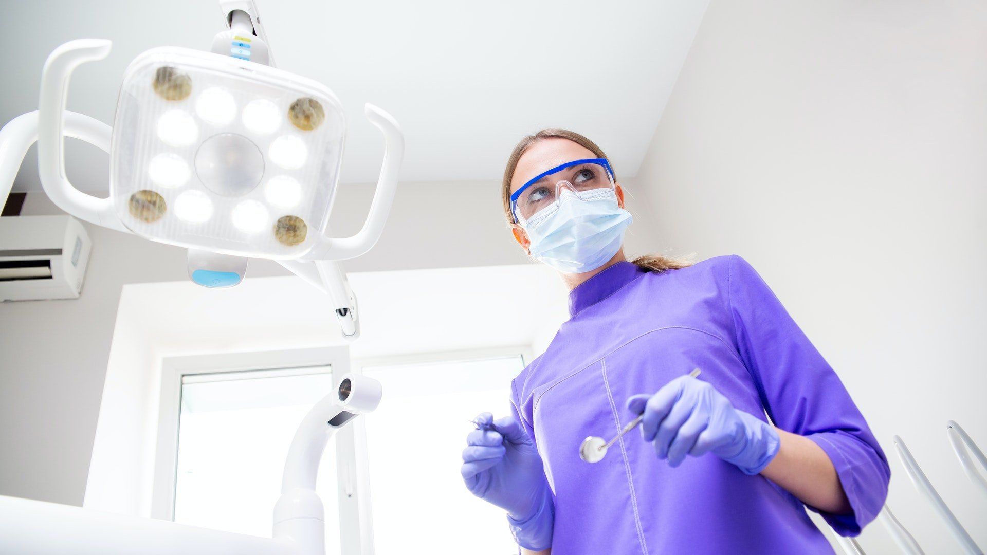 A female dentist wearing a mask and gloves is working in a dental office.