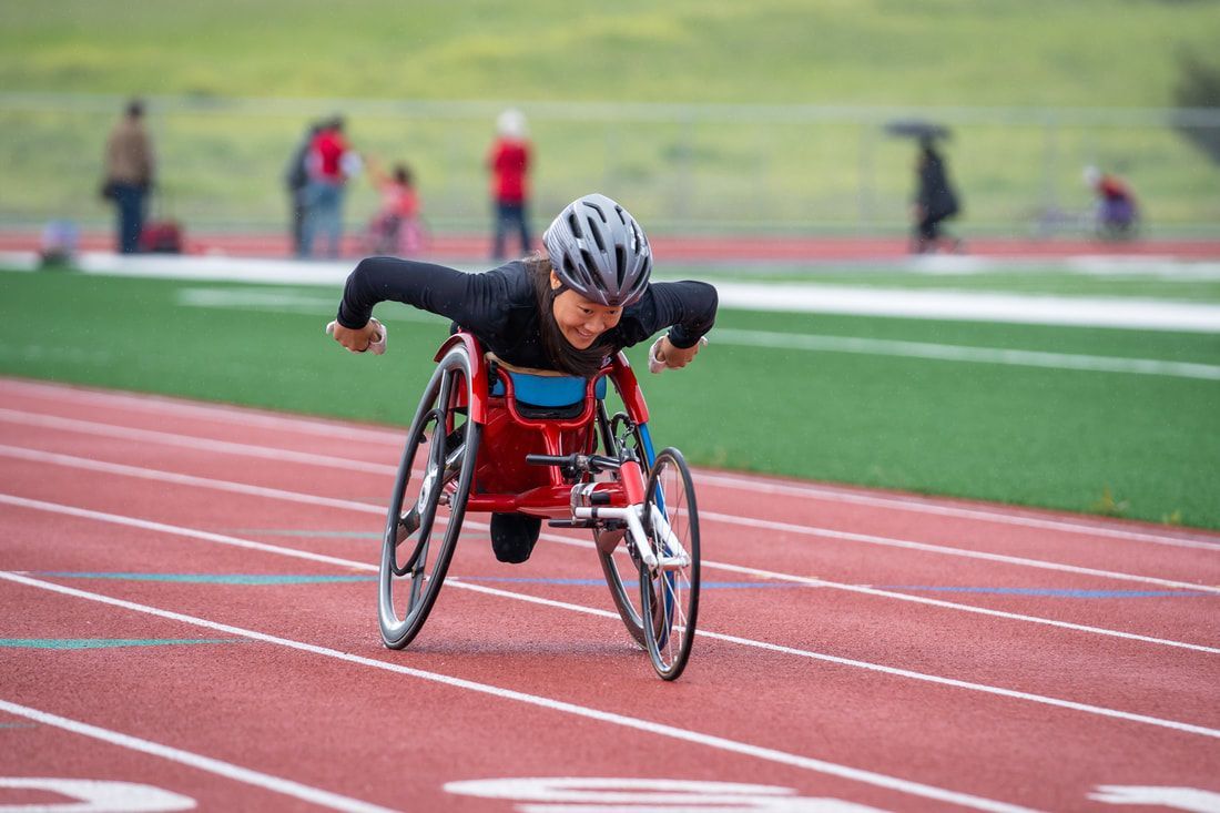 Elizabeth Floch leans low in a red racing wheelchair on the track