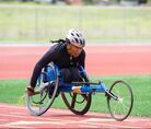 Lauren Fields races a blue racing wheelchair on the track