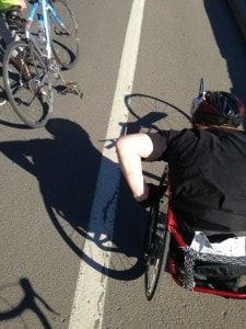 Racer in a racing wheelchair pushes alongside cyclists, seen from above