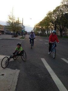 Athlete in a racing wheelchair rides a city street with cyclists behind