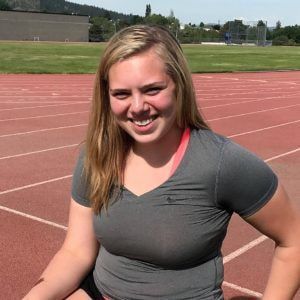 Sophie Munter smiles in a gray T-shirt at the track