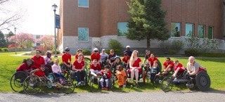 Large ParaSport group in red shirts poses on a lawn with their wheelchairs