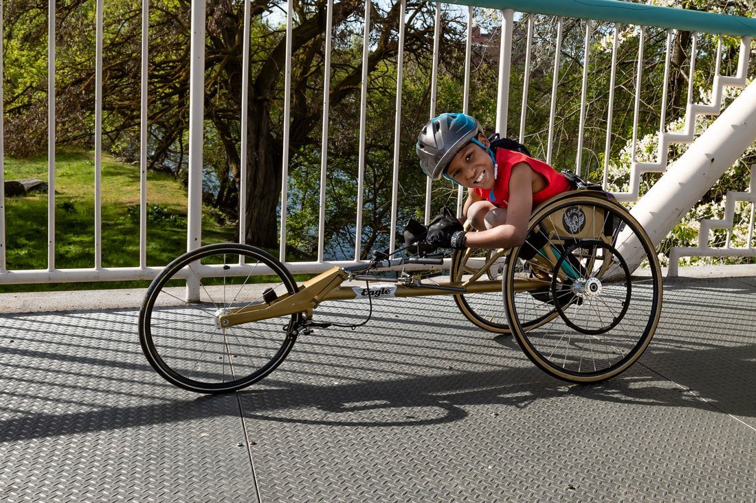 Smiling young racer in a red shirt lies forward in a gold racing chair