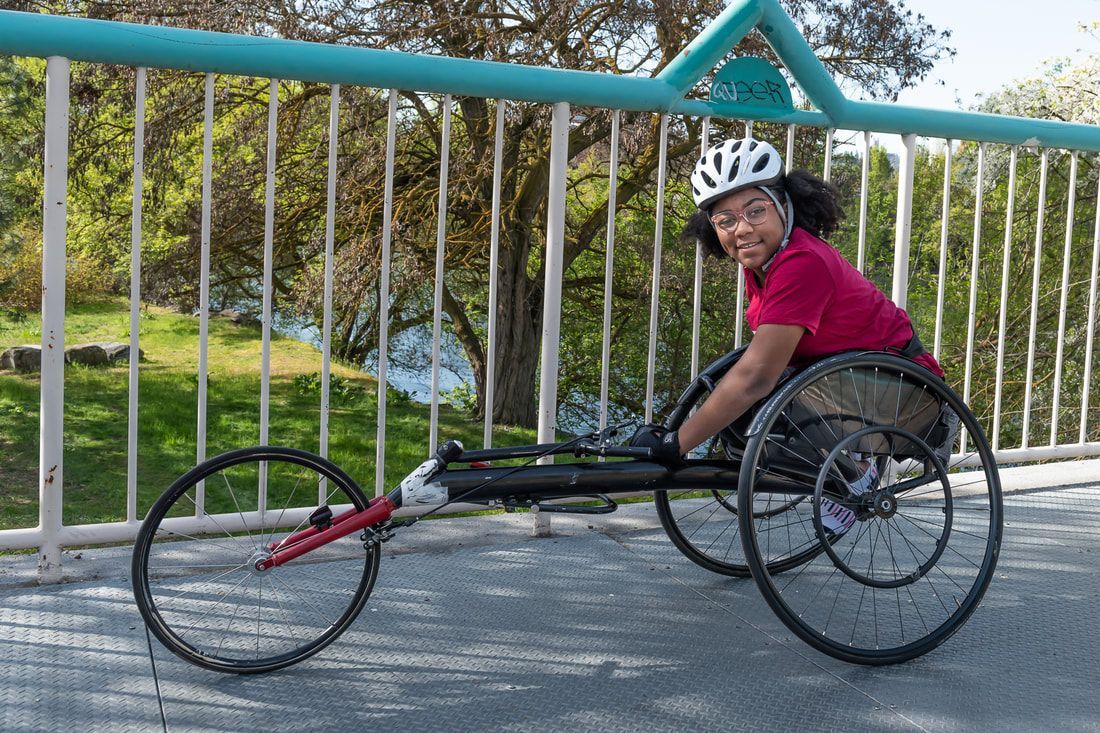 Racer in a maroon shirt and white helmet smiles from a black racing chair