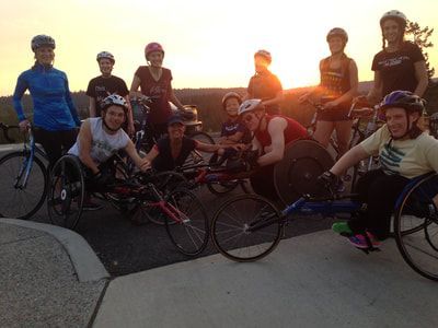 Racers and cyclists pose together at sunset after a training ride