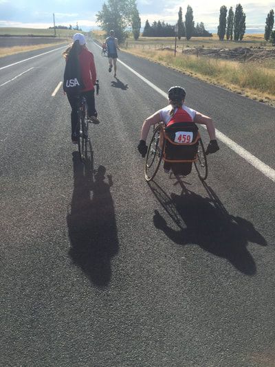 Racer with bib 459 pushes along a rural highway beside a cyclist