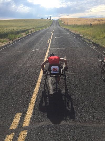 Racer with bib 460 pushes down an open road between wheat fields