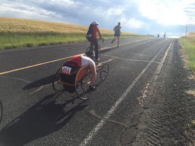 Racer with bib 459 trails a cyclist and a runner on a rural road