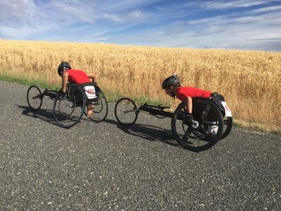 Two racers in red push past a golden wheat field