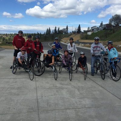 Large group of racers and cyclists pose on a plaza under a blue sky