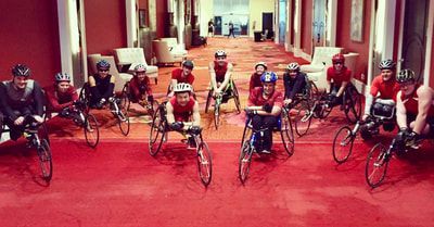 Large group of racers in red lines up in a hotel lobby before a race