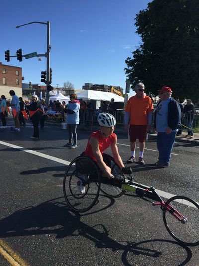 Racer in a red shirt waits on a downtown street lined with spectators