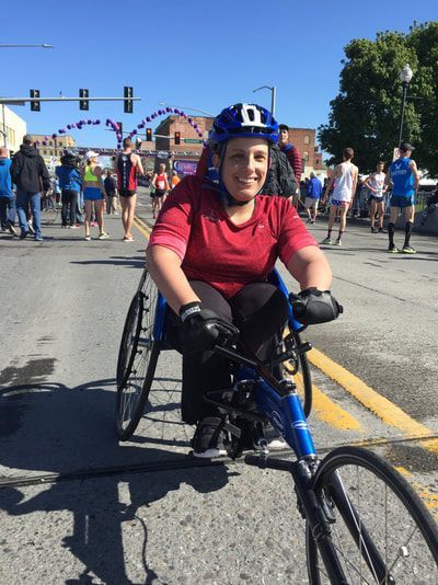 Racer in a red shirt and blue helmet smiles on race morning downtown