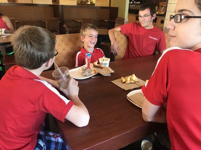 Athletes in red ParaSport shirts share a meal at a restaurant table