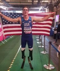 Paralympian Nick Rogers on running blades holds a U.S. flag behind him