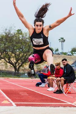 Long jumper with a prosthetic leg flies through the air, arms raised