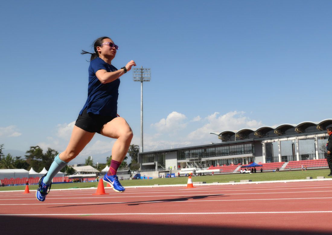 Taylor Swanson in sunglasses strides down the track under a blue sky