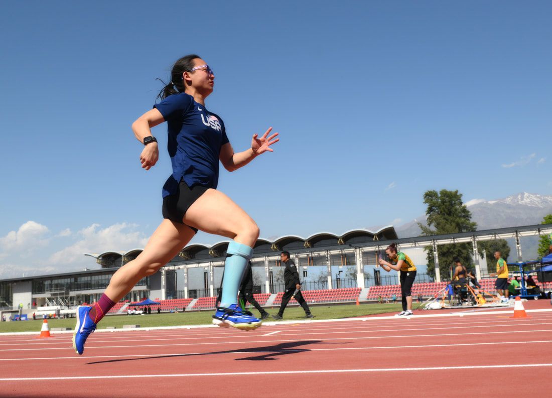 Taylor Swanson in navy races along the track, mountains behind