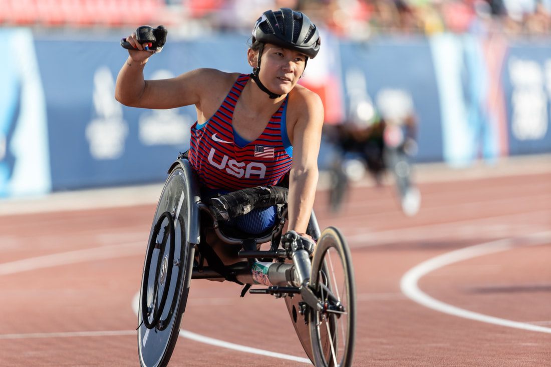 Hannah Dederick raises a fist from her racing wheelchair
