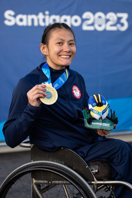 Hannah Dederick holds up her medal and the Santiago 2023 mascot