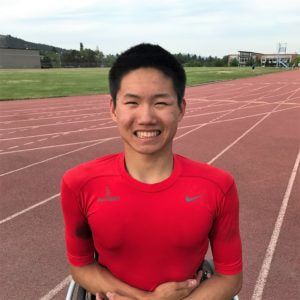 Phillip Croft smiles in a red shirt on the track