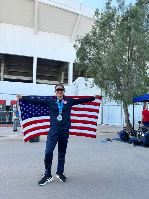 Team USA athlete with a medal spreads an American flag outside the stadium