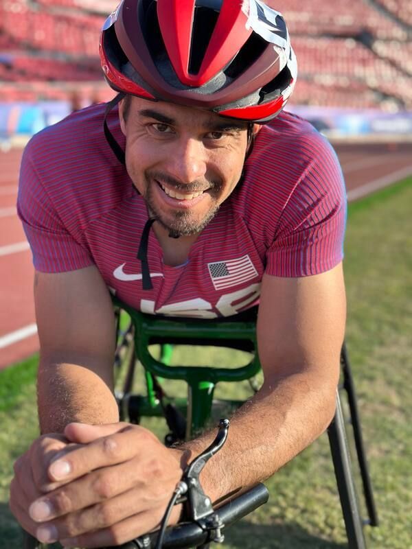 Smiling wheelchair racer in a red helmet and maroon Team USA top