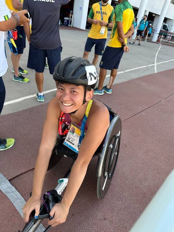 Smiling wheelchair racer in a black helmet and credential by the track