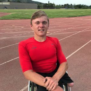 Spencer Kimbro in a red shirt sits in his wheelchair on the track