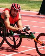 Wheelchair racer in a red helmet and top pushes down the track