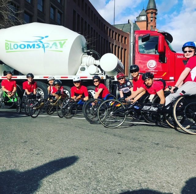 ParaSport Spokane racers in red line up by a Bloomsday cement mixer truck