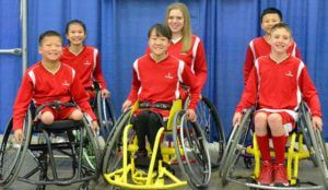 2016 youth team in red warm-ups poses in front of a blue curtain