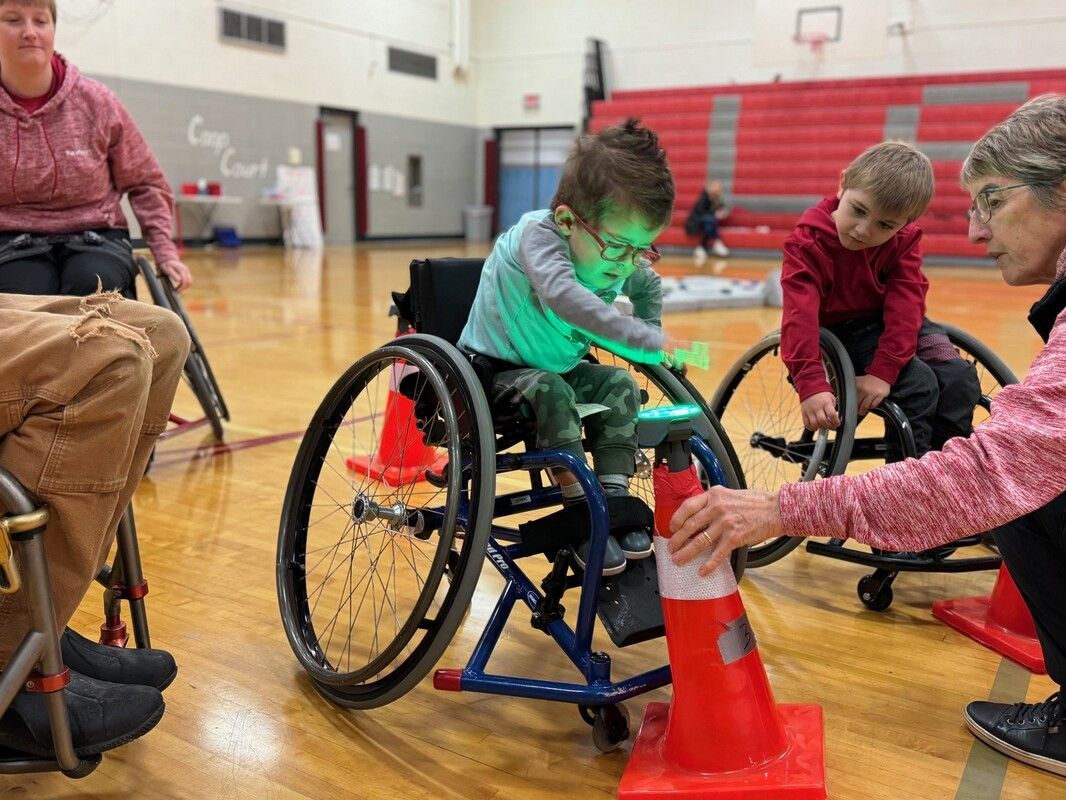 Young athlete in a sports wheelchair weaves past cones during Futures play