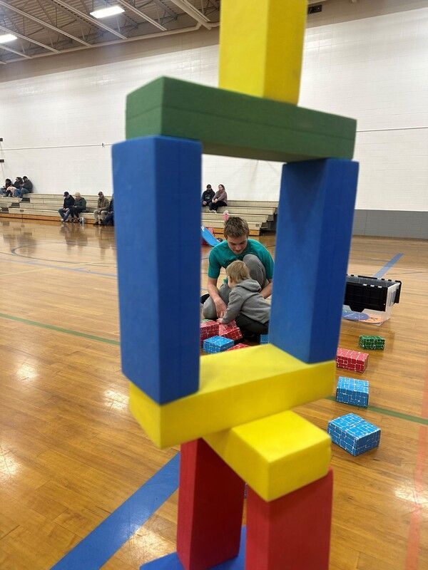 Tower of colorful foam blocks with Futures players in the gym behind it