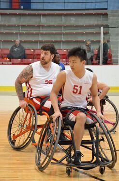 Wheelchair basketball players in white jerseys 25 and 51 during a game