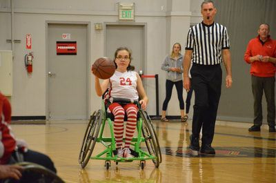 Player in jersey 24 and striped socks brings the ball up court
