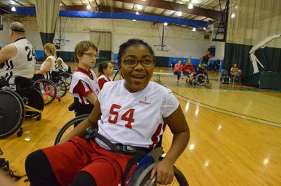 Player in jersey 54 and glasses grins at the camera in a busy gym