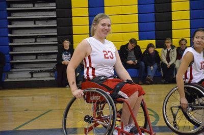 Player in white jersey 23 smiles on court with spectators behind her
