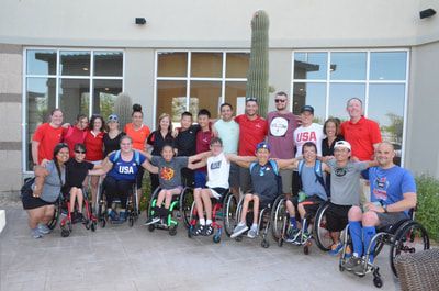 Athletes and coaches pose for a group photo beside a tall cactus