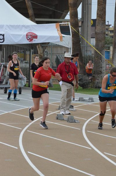 Sprinter in a red T-shirt pushes off at the start beside an official