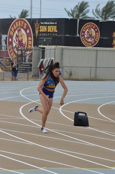Sprinter in blue leaves the start in front of Sun Devil Athletics signs