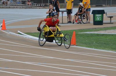 Racer in a yellow racing wheelchair rounds the cones on the bend