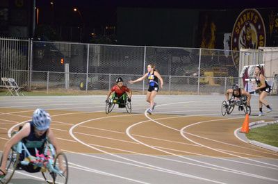 Racer in a blue helmet heads out as racers and runners round the bend at night