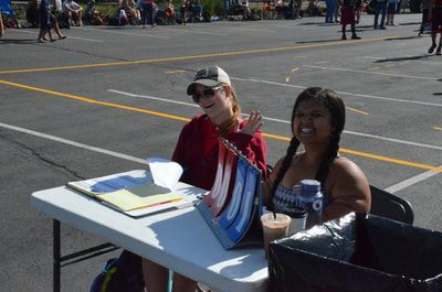 Two women smile at the scorer's table beside the wheelchair court