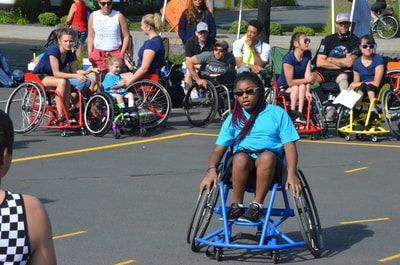 Girl in a light blue shirt and sunglasses rolls forward, teammates behind