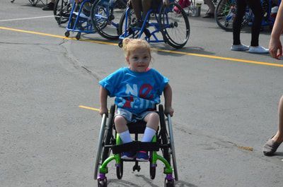 Small child in a blue No Excuses shirt rolls toward the camera