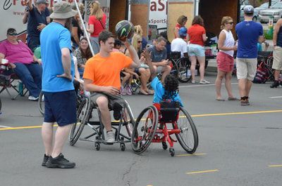 Child in a red wheelchair shoots as a player in orange defends