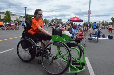 Smiling player in orange sits beside an empty green sport wheelchair