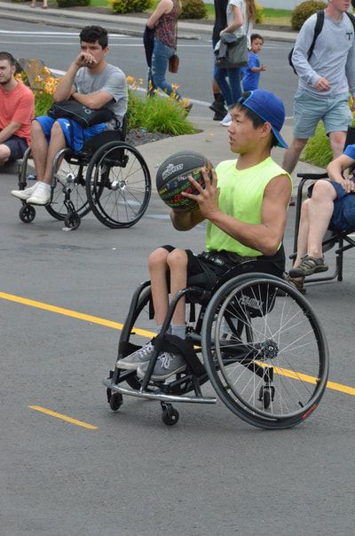 Young man in a neon yellow tank and blue cap holds the ball, ready to shoot